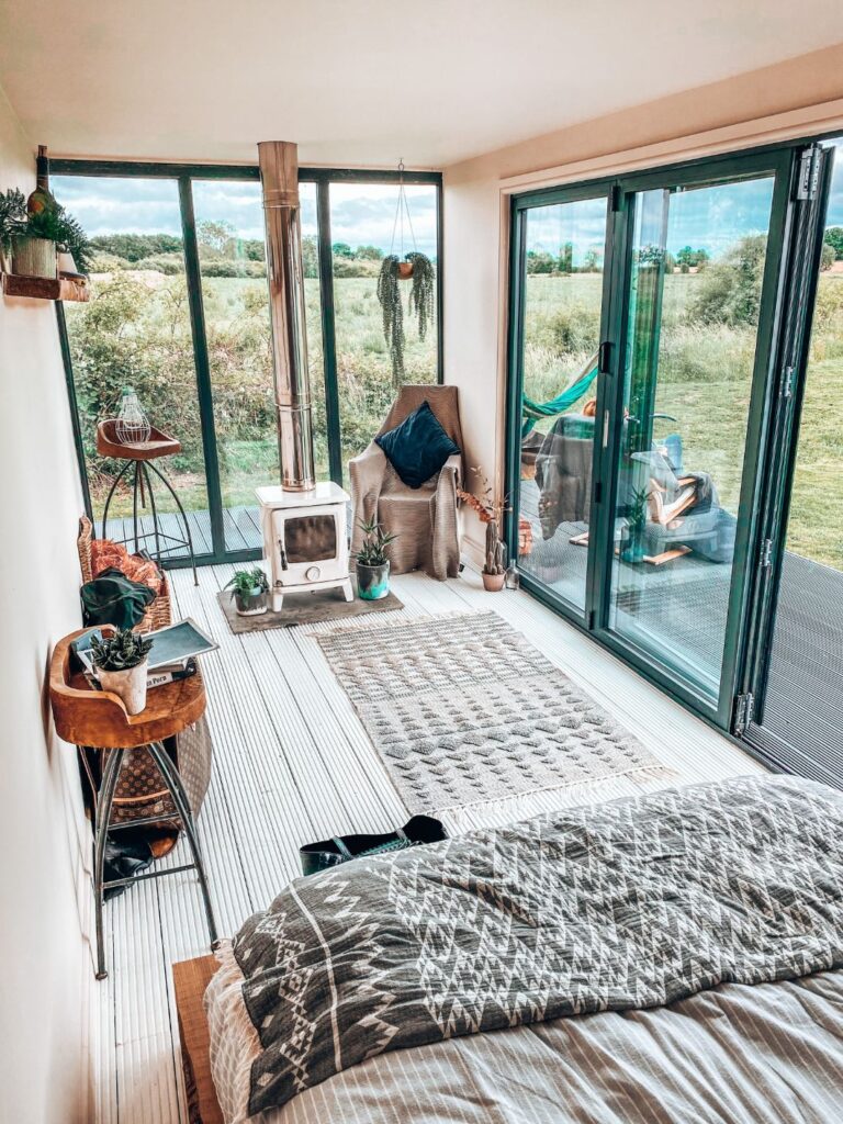 An old shipping container converted into a beautiful room with log burner and bed