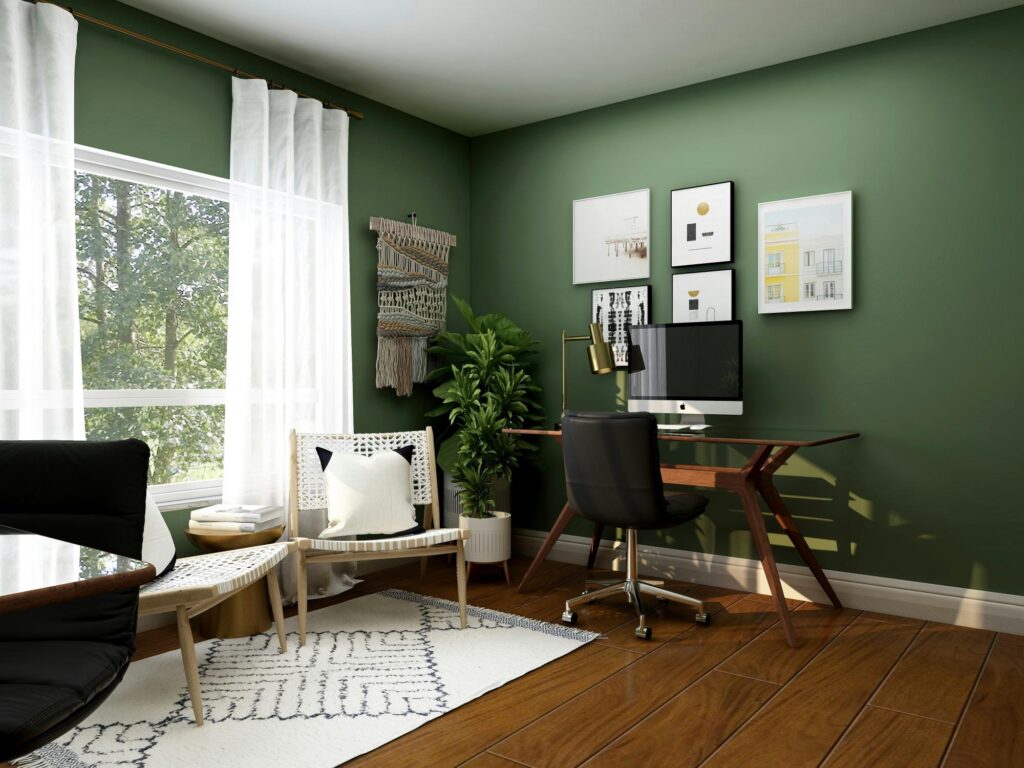 A home ofice with dark green walls and dark wood flooring