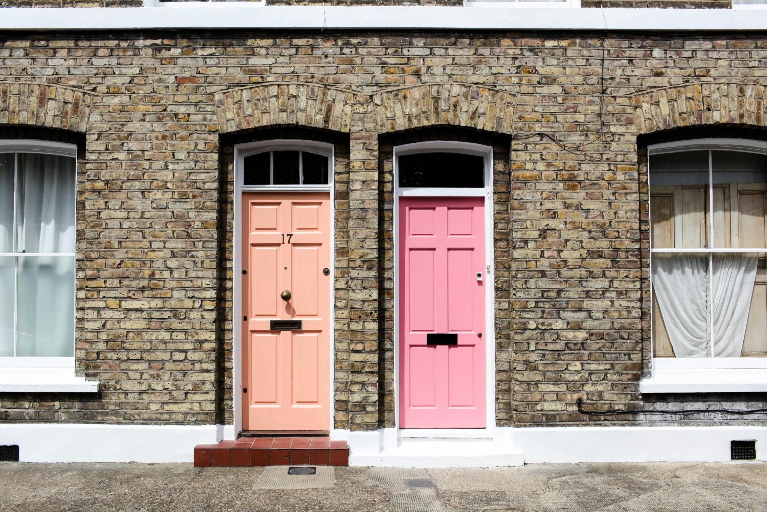 Neighbouring terraced houses, one with an orange door and one pink